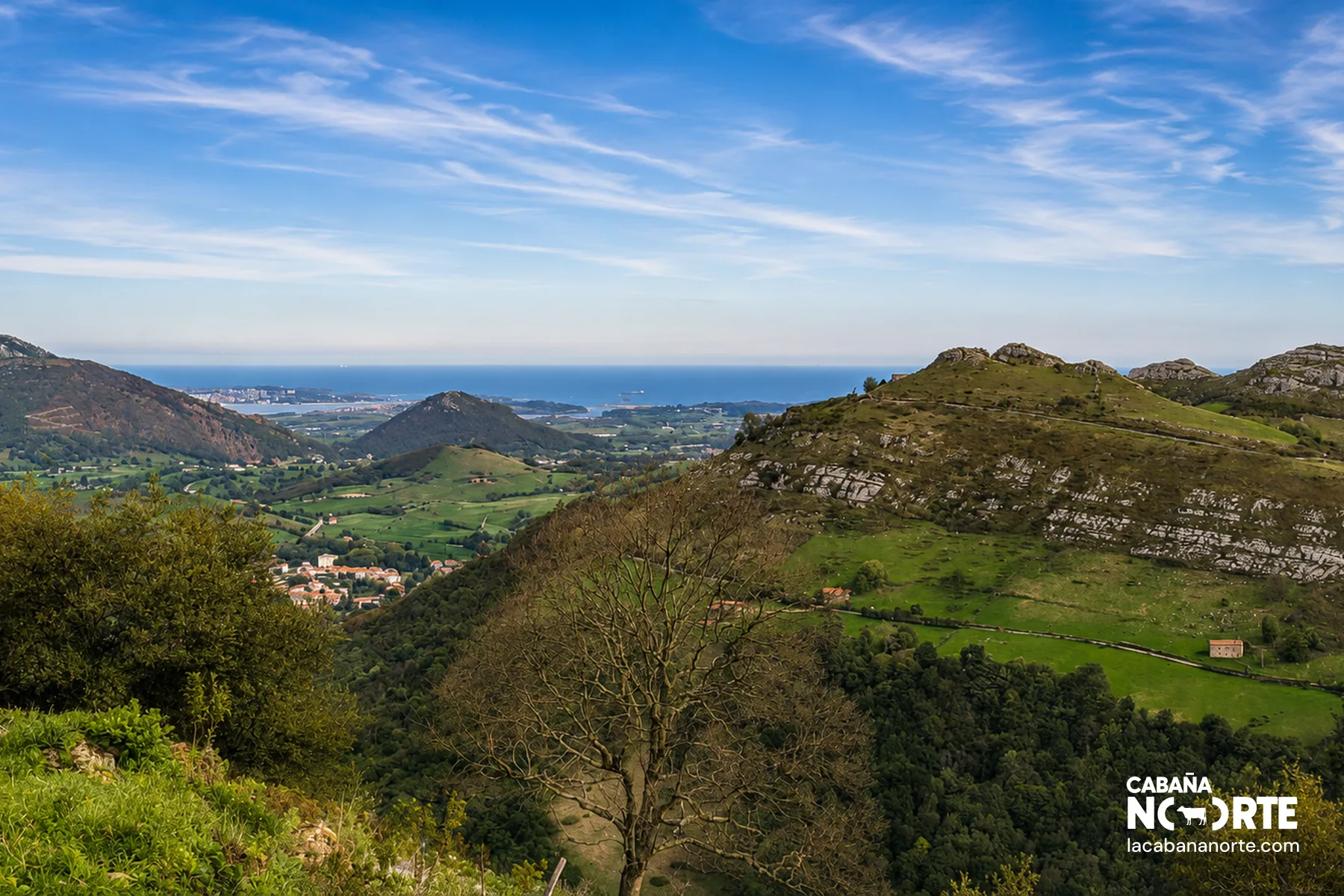 Vista de un valle pasiego en San Pedro de Romeral, con praderas, cabañas dispersas y montañas verdes característicos de los Valles Pasiegos