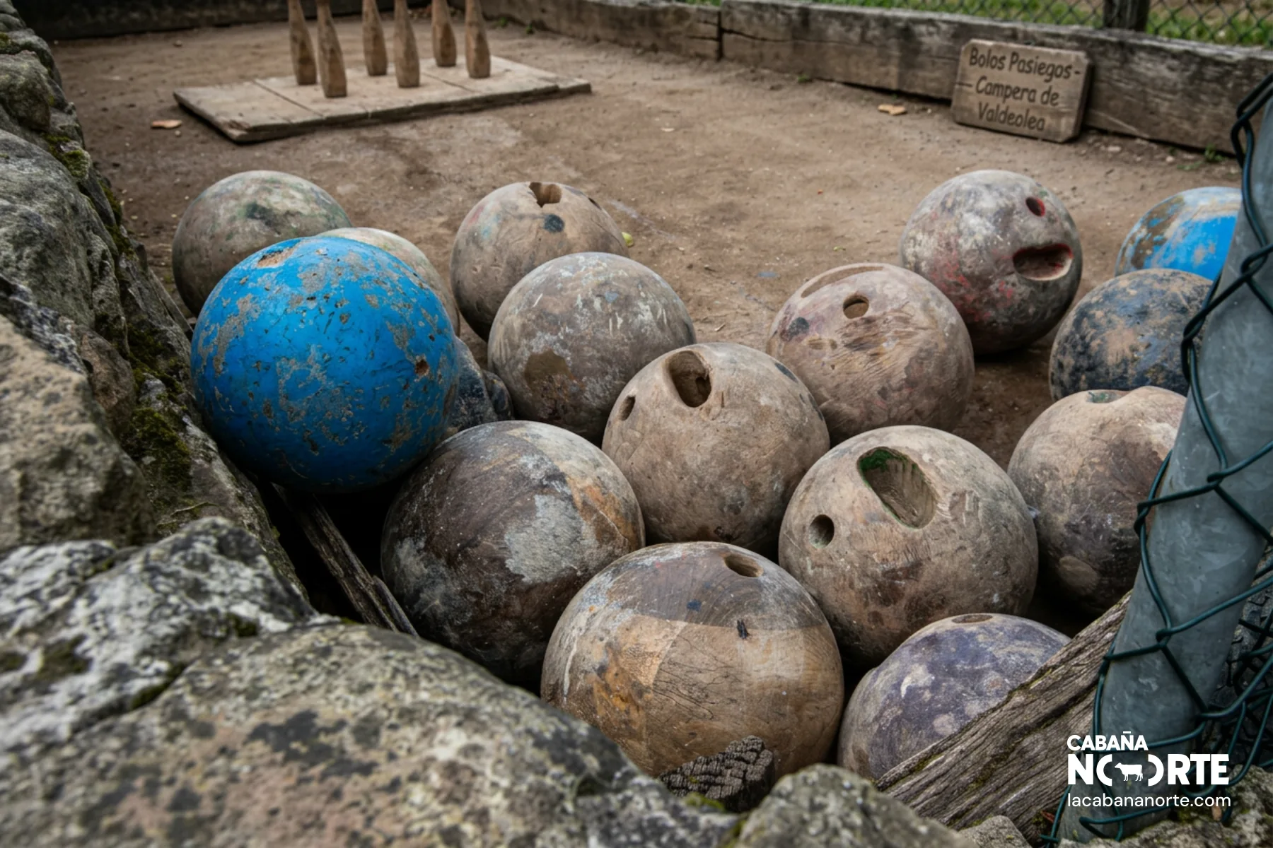 Conjunto de bolas de bolos pasiegos desgastadas junto a pista tradicional de tierra